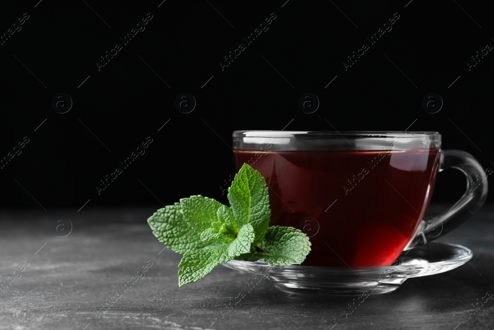 Photo of Cup of hot aromatic tea with mint on grey table. Space for text