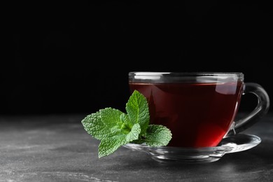 Cup of hot aromatic tea with mint on grey table. Space for text