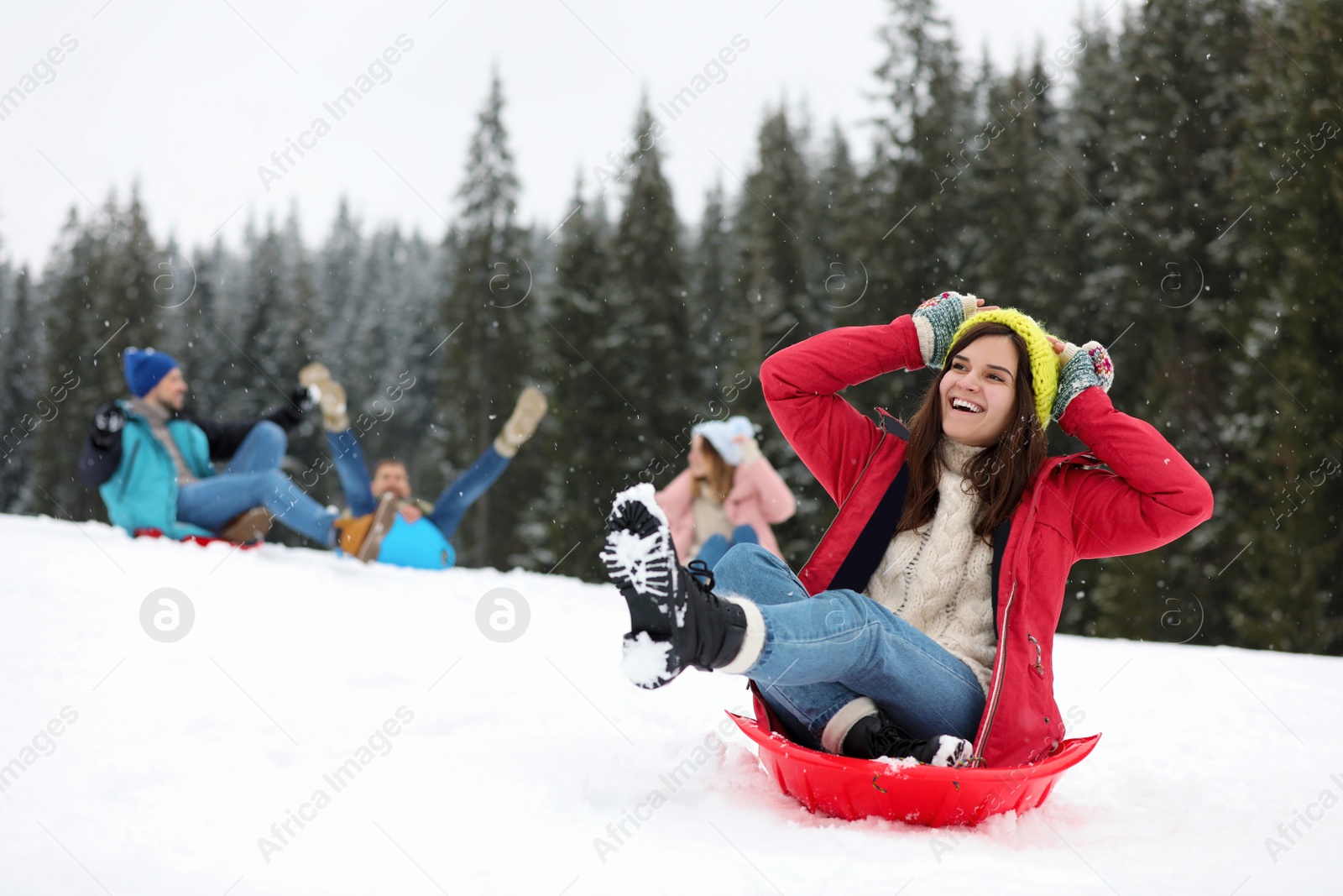 Photo of Happy friends sliding on sleds outdoors. Winter vacation