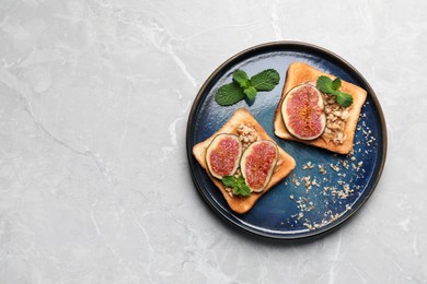 Photo of Tasty toasts with fig pieces, peanut butter and walnuts on light grey marble table, top view. Space for text