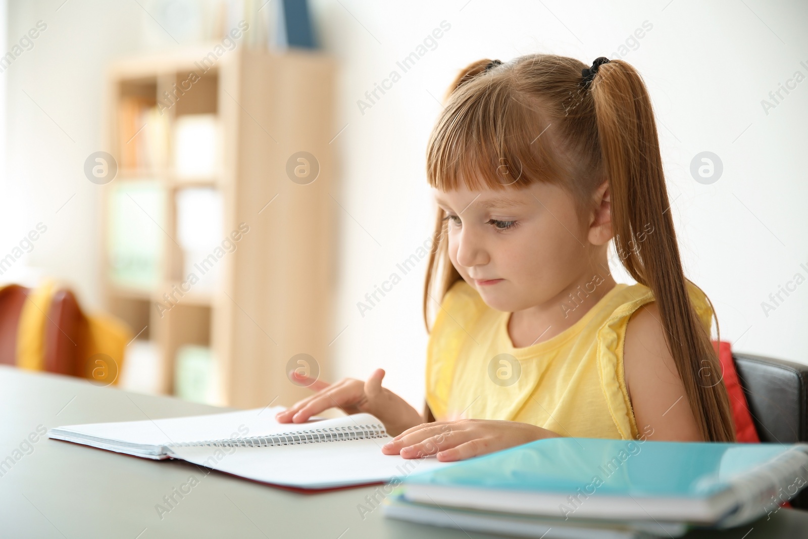 Photo of Cute little child doing assignment at desk in classroom. Elementary school