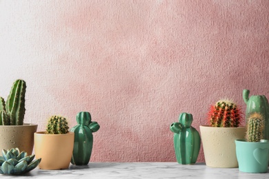 Different potted cacti on table near color background, space for text. Interior decor