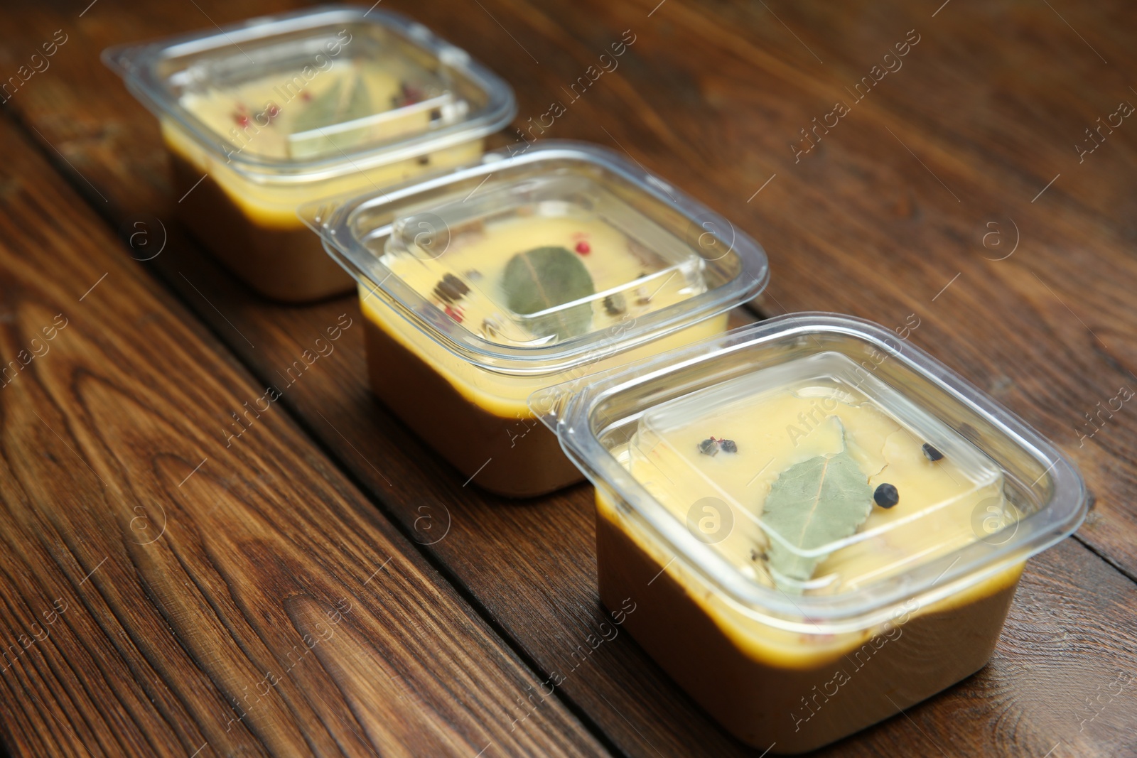 Photo of Delicious chicken liver pate in plastic containers on wooden table. Food delivery service