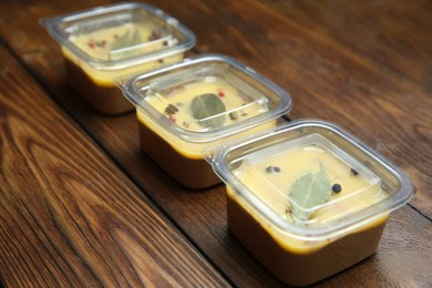 Photo of Delicious chicken liver pate in plastic containers on wooden table. Food delivery service