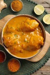 Tasty chicken curry and ingredients on wooden table, top view