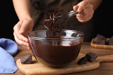 Photo of Woman making delicious chocolate cream at wooden table, closeup