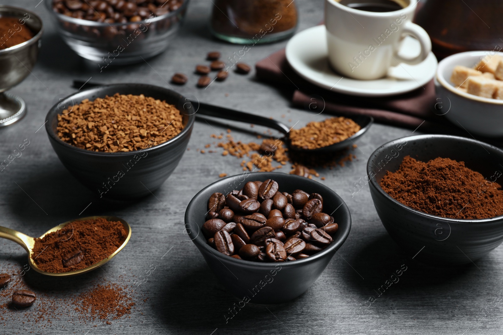 Photo of Bowls of beans, instant and ground coffee on grey table