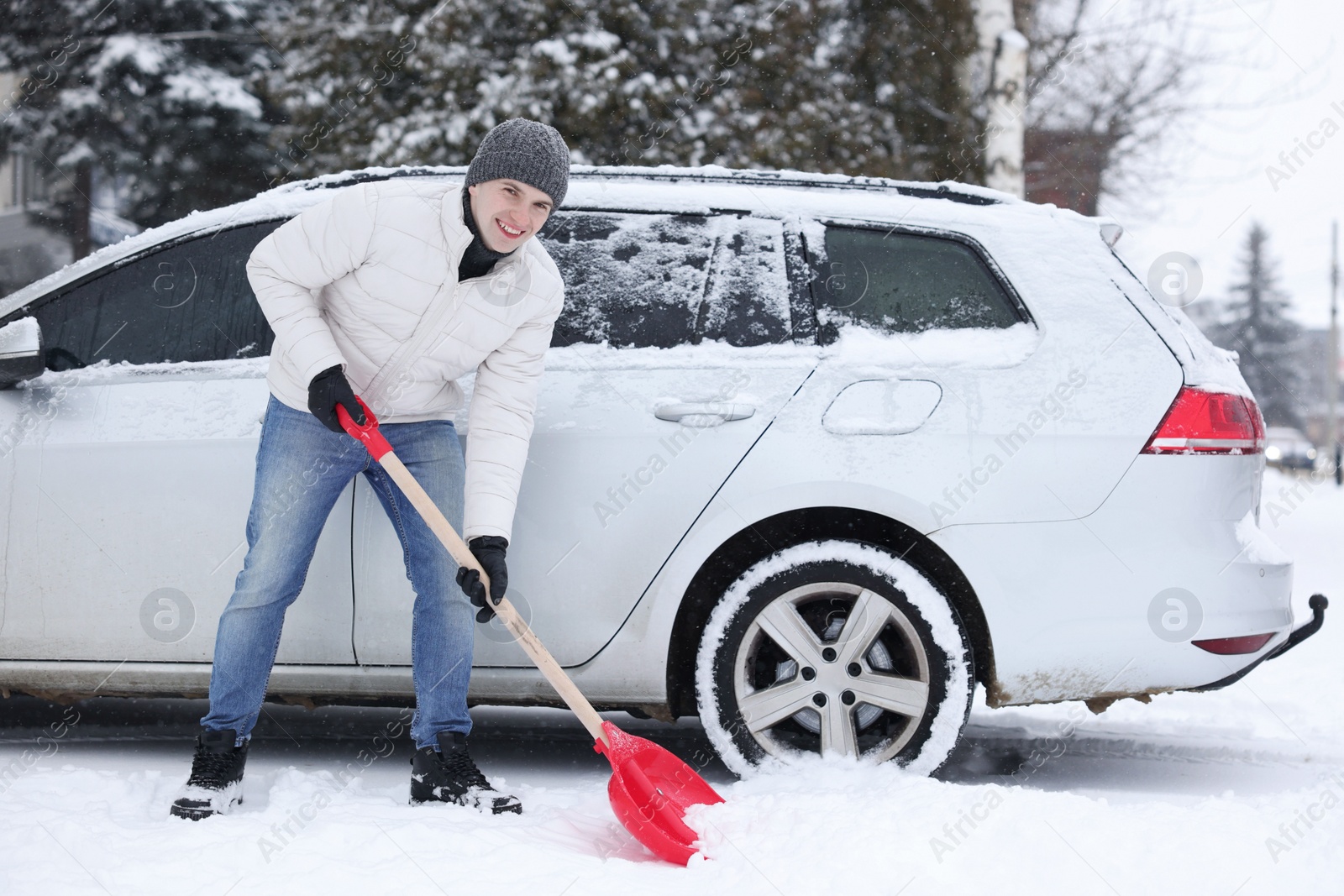 Photo of Man removing snow with shovel near car outdoors