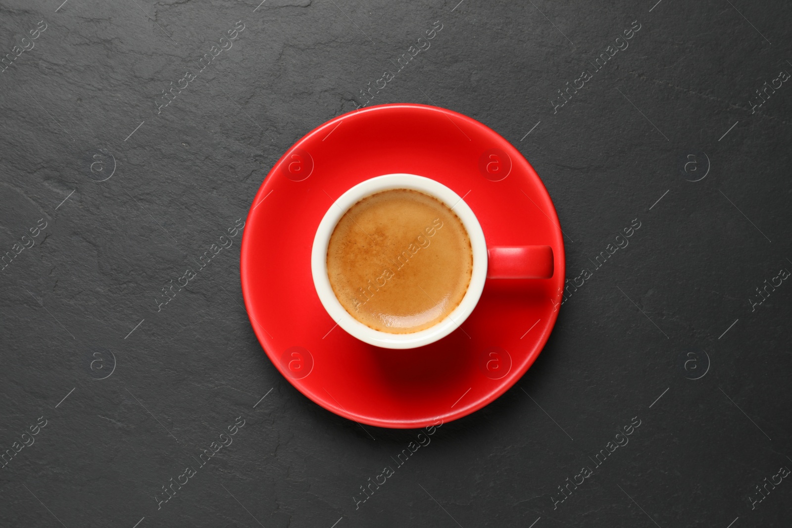 Photo of Aromatic coffee in red cup on black background, top view