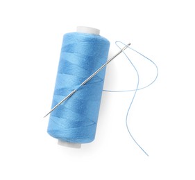 Photo of Spool of light blue sewing thread with needle isolated on white, top view