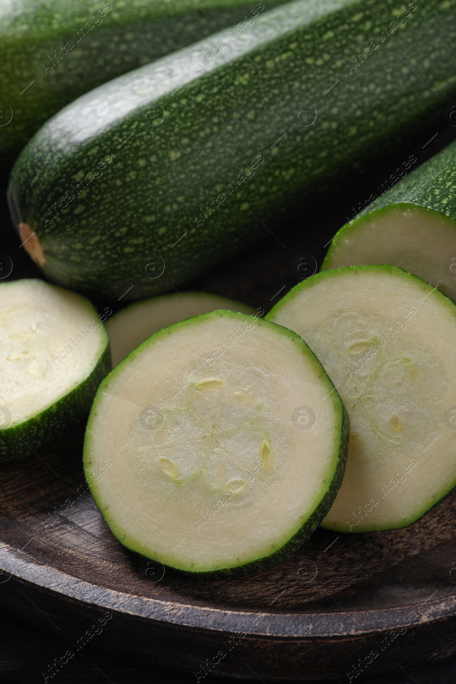 Photo of Whole and cut ripe zucchinis on plate, closeup