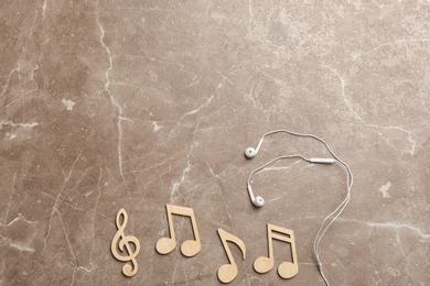 Photo of Flat lay composition with music notes, earphones and space for text on color background