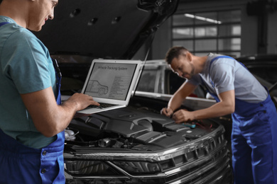 Photo of Mechanic with laptop doing car diagnostic at automobile repair shop