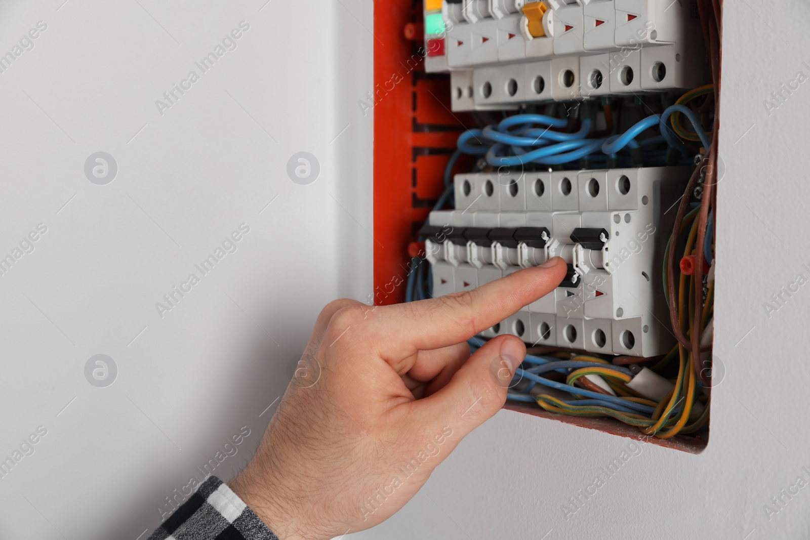 Photo of Handyman pressing switch on electrical panel board indoors, closeup