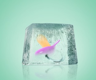 Image of Conservation of genetic material. Baby pacifier in ice cube as cryopreservation on mint color background