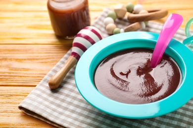 Photo of Bowl of healthy baby food on wooden table, closeup. Space for text