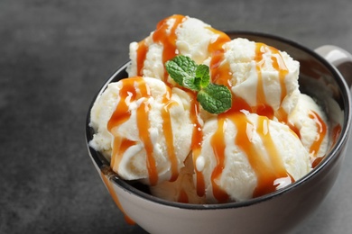 Tasty ice cream with caramel sauce in mug on table, closeup