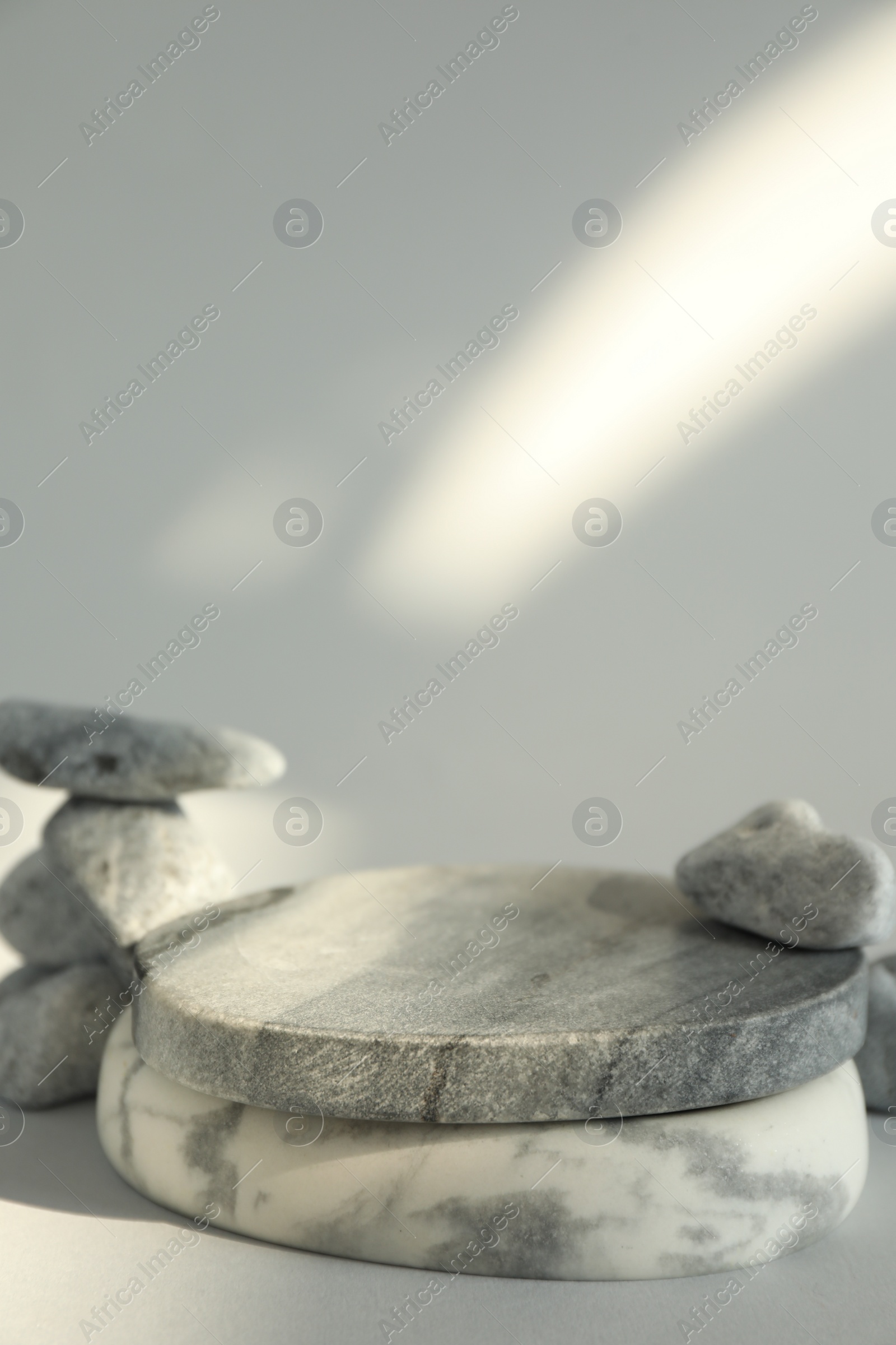 Photo of Presentation for product. Stone podium and pebbles on light grey background. Space for text