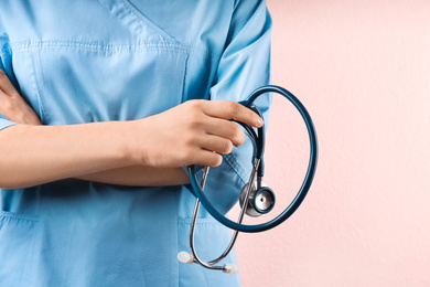 Photo of Doctor with stethoscope on pink background, closeup. Medical service