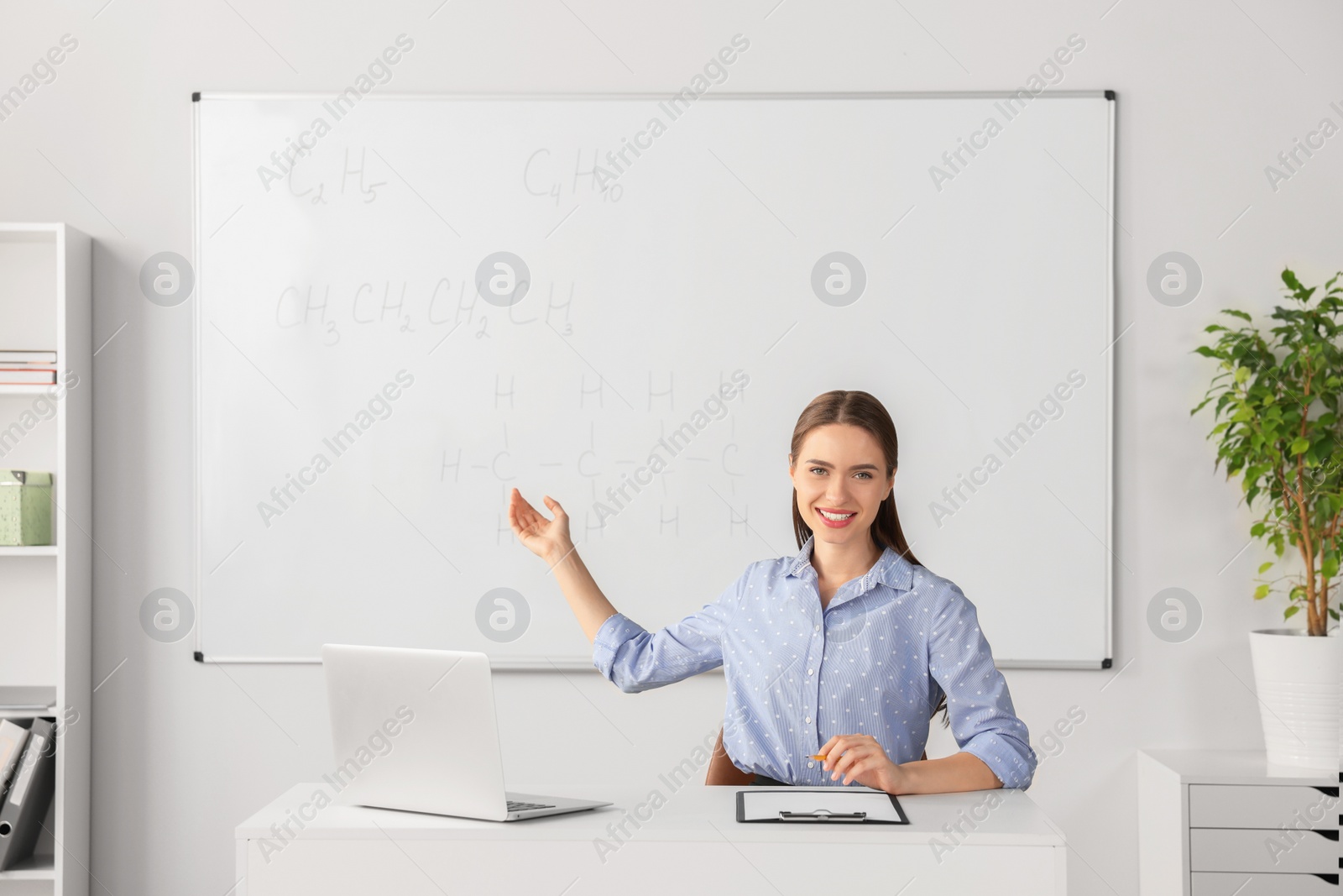 Photo of Young chemistry teacher giving lesson at table in classroom