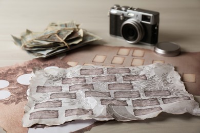Photo of Papers with family tree templates, vintage camera and photos on light wooden table, closeup