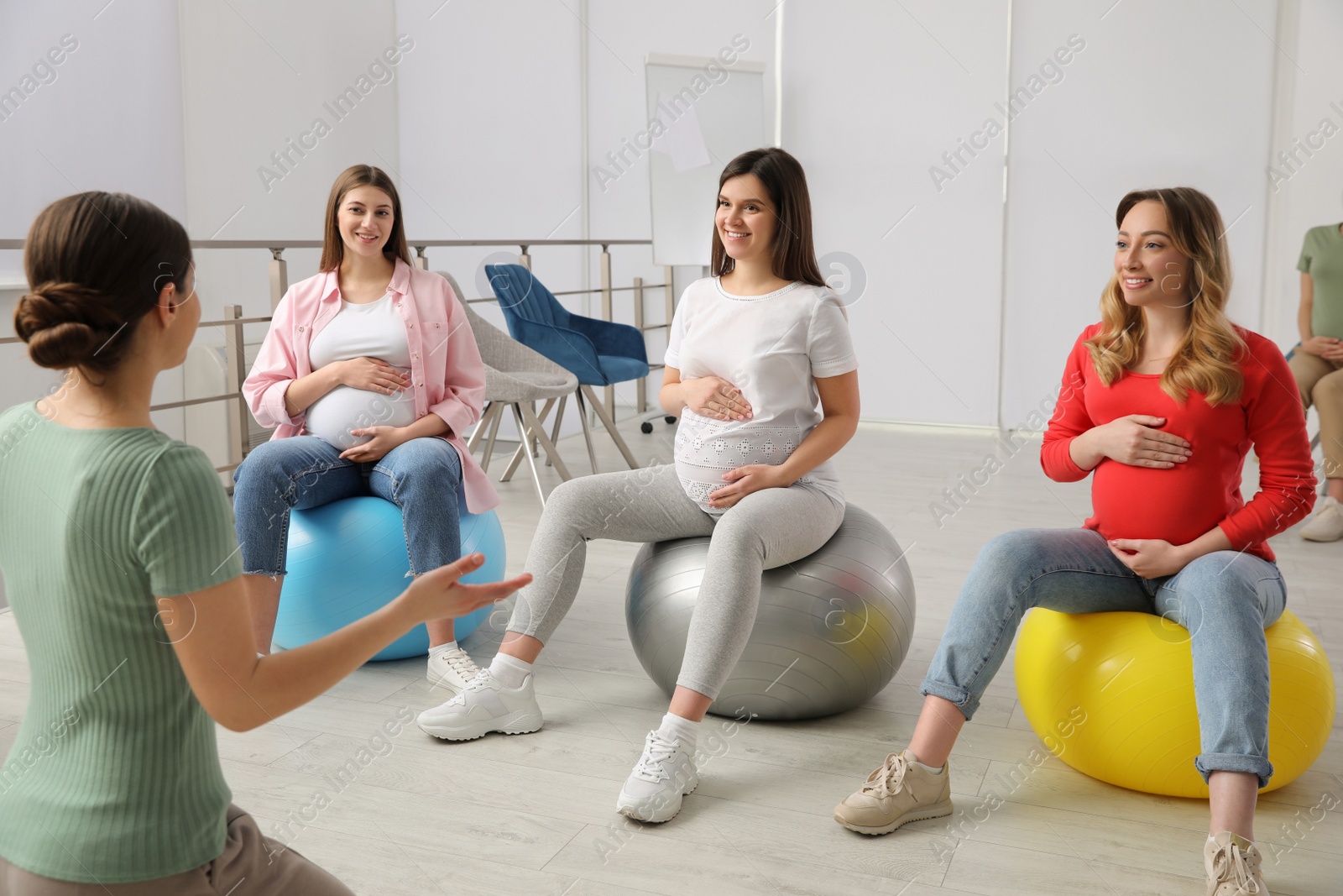 Photo of Group of pregnant women with trainer at courses for expectant mothers indoors