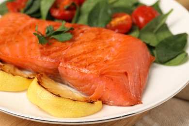 Photo of Tasty grilled salmon with basil, tomatoes and lemon on table, closeup