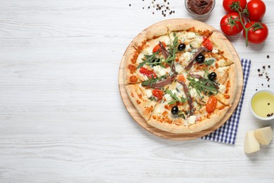 Tasty pizza with anchovies and ingredients on white wooden table, flat lay. Space for text