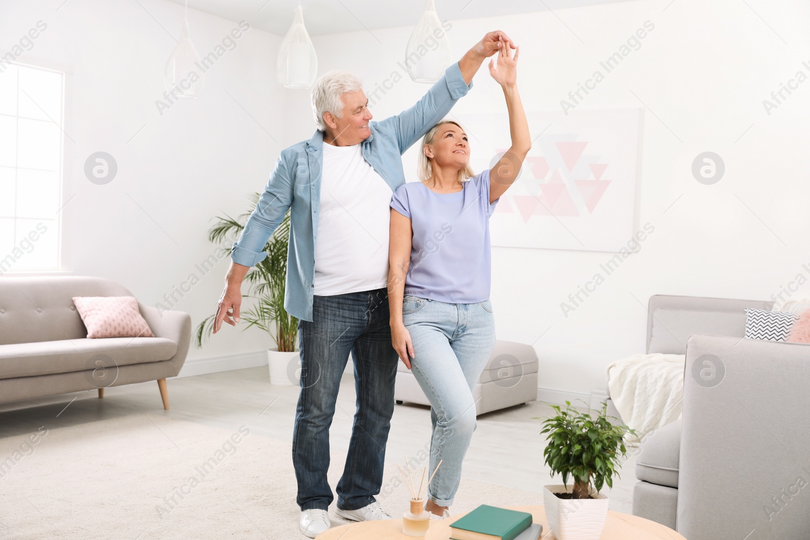 Photo of Happy mature couple dancing together in living room