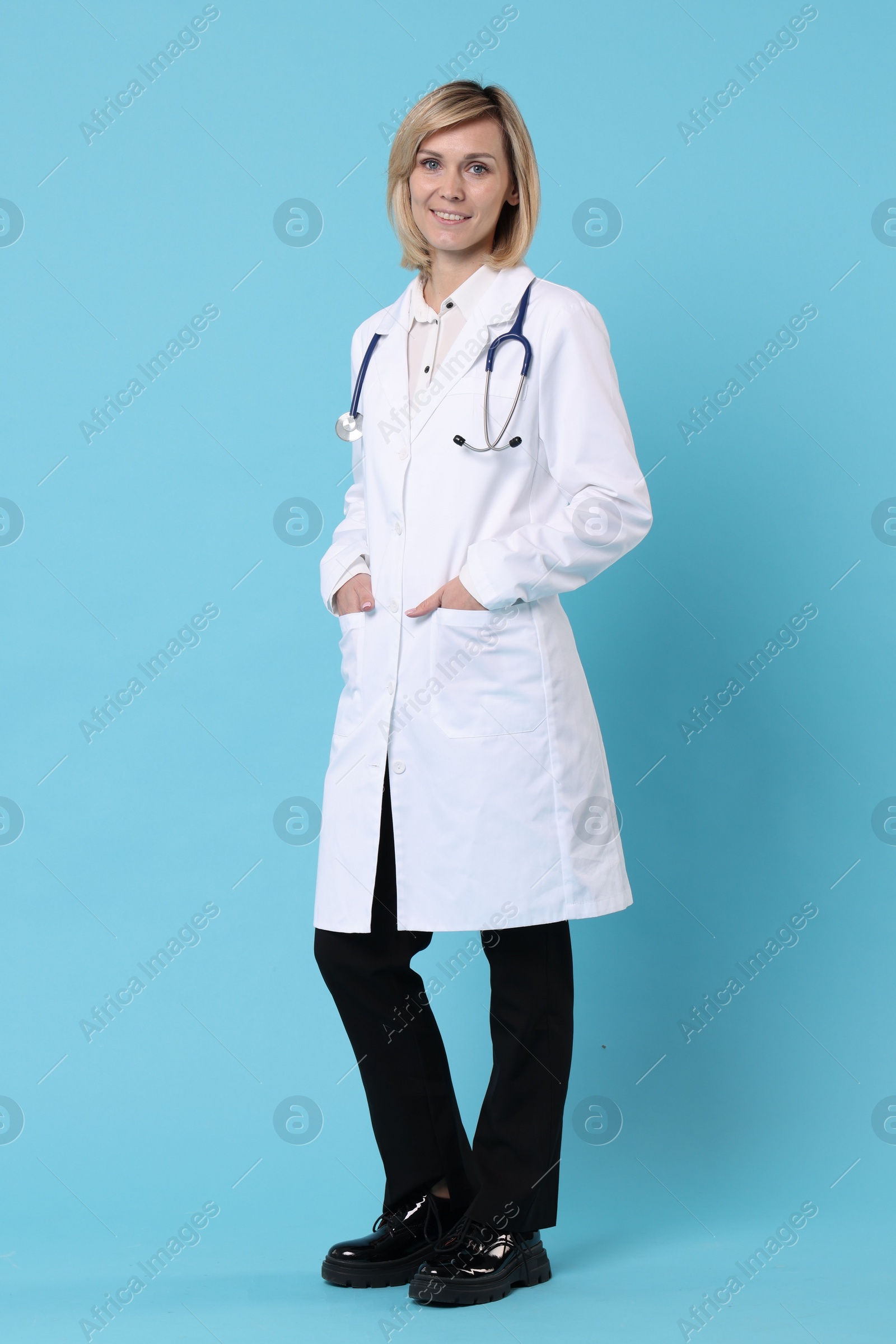 Photo of Smiling doctor in uniform on light blue background