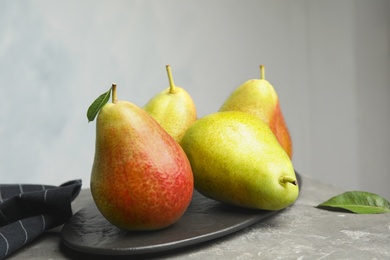 Photo of Ripe juicy pears on stone table against grey background