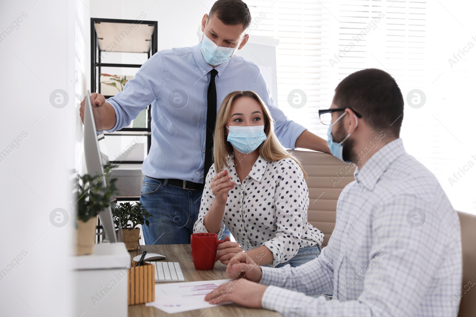 Photo of Coworkers with masks in office. Protective measure during COVID-19 pandemic