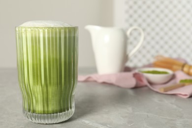 Glass of tasty matcha latte on light gray marble table, space for text