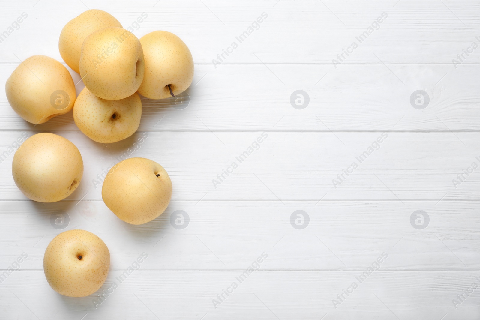 Photo of Ripe apple pears on white wooden table, flat lay. Space for text