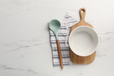 Empty ceramic pot, ladle and board on white marble table, top view. Space for text