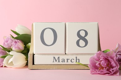 Wooden block calendar with date 8th of March and tulips on pink background. International Women's Day
