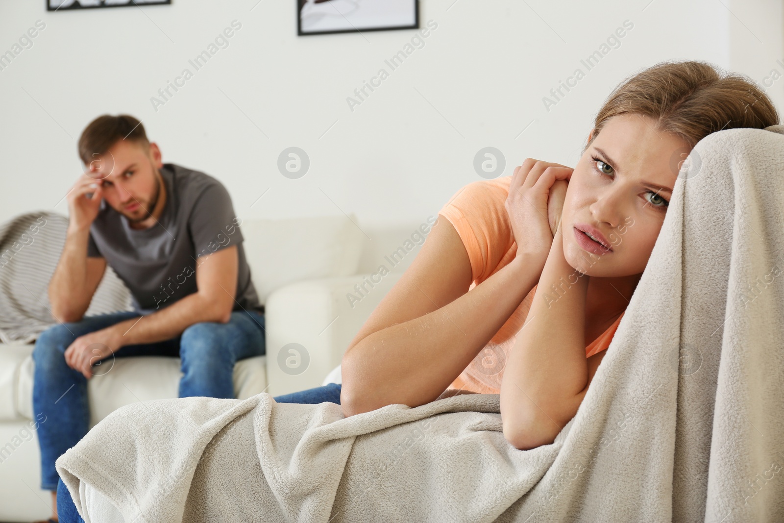 Photo of Young couple ignoring each other after argument in living room. Relationship problems