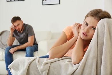 Photo of Young couple ignoring each other after argument in living room. Relationship problems