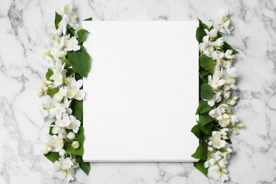 Blank canvas and beautiful jasmine flowers on white marble table, flat lay. Space for design