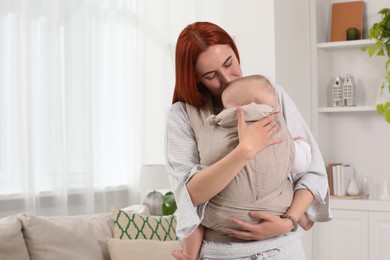 Photo of Mother holding her child in sling (baby carrier) at home