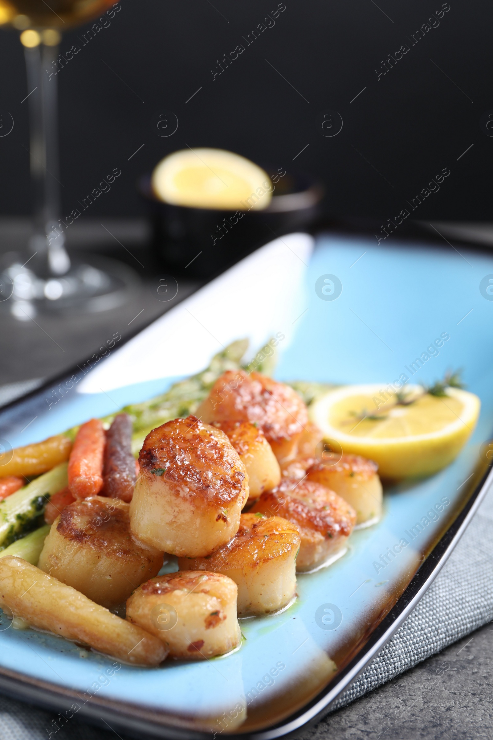 Photo of Delicious fried scallops with asparagus served on grey table