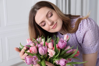 Young woman with bouquet of beautiful tulips indoors