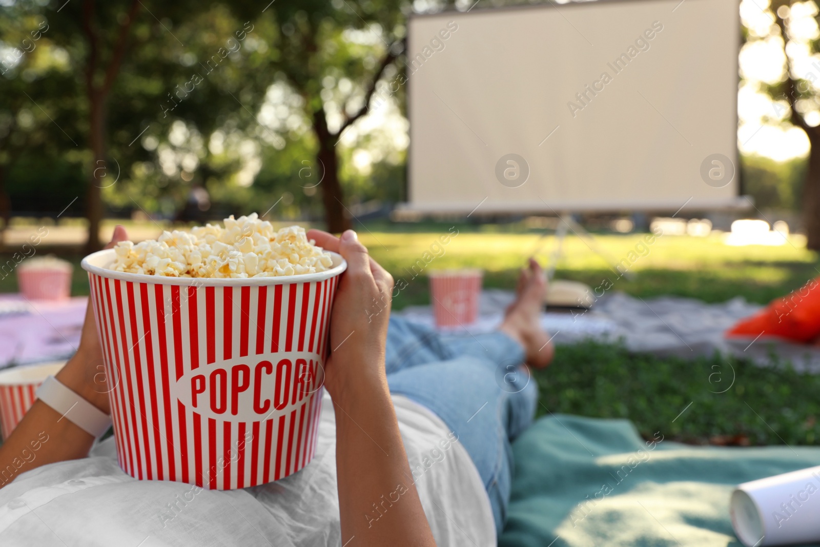 Photo of Woman with popcorn watching movie in open air cinema, closeup. Space for text