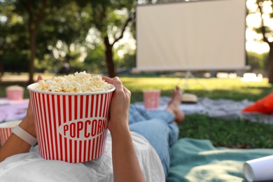 Woman with popcorn watching movie in open air cinema, closeup. Space for text