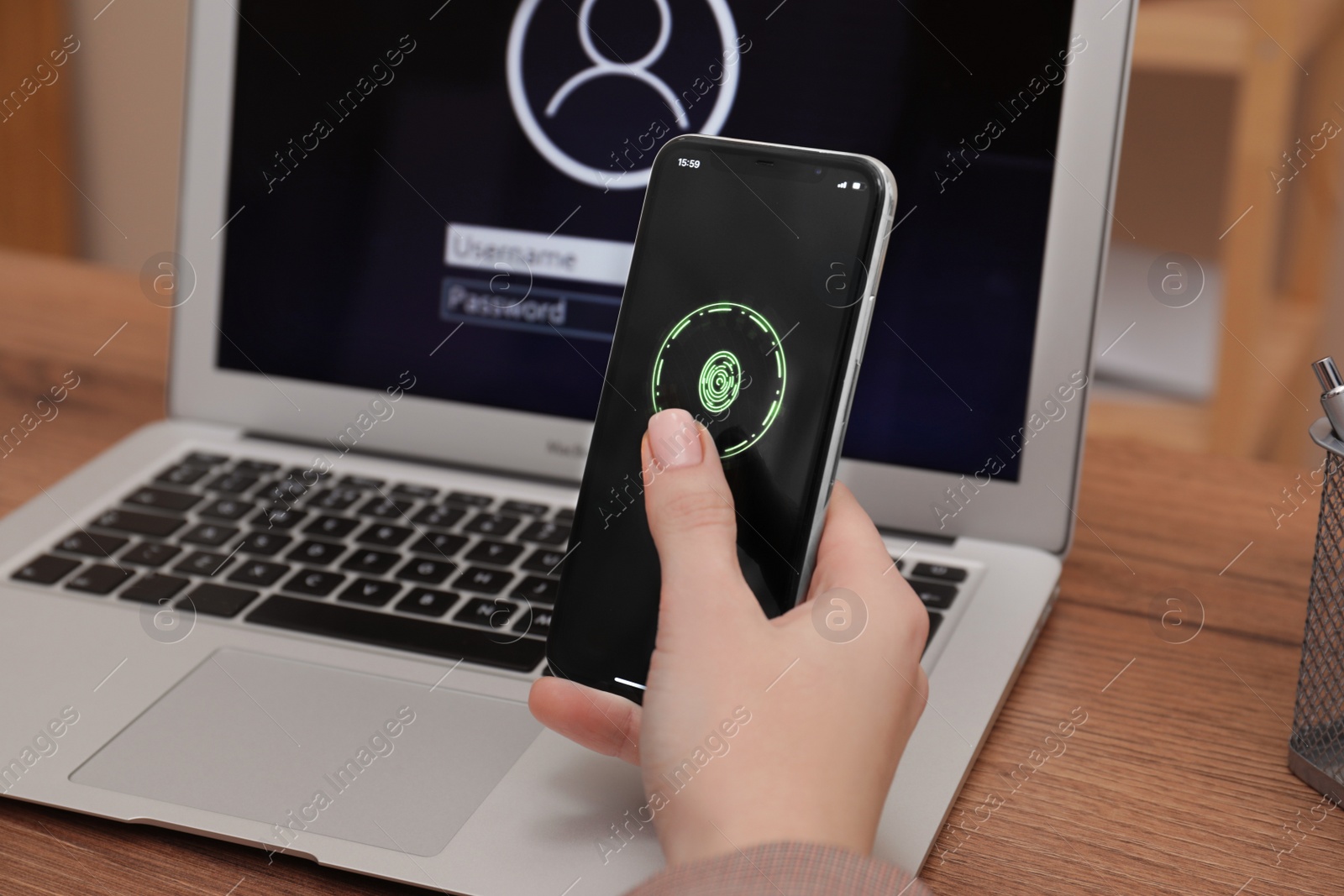 Photo of Woman holding blocked smartphone with fingerprint identification near laptop at workplace , closeup. Reliable password