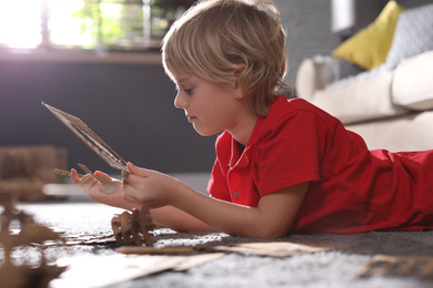 Little boy making cardboard toys on floor at home. Creative hobby