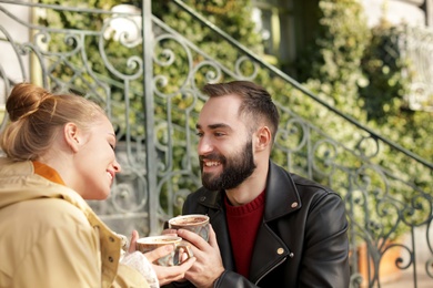 Photo of Lovely young couple enjoying tasty coffee outdoors
