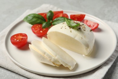 Delicious mozzarella with tomatoes and basil leaves on table, closeup