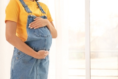 Beautiful pregnant woman near window at home