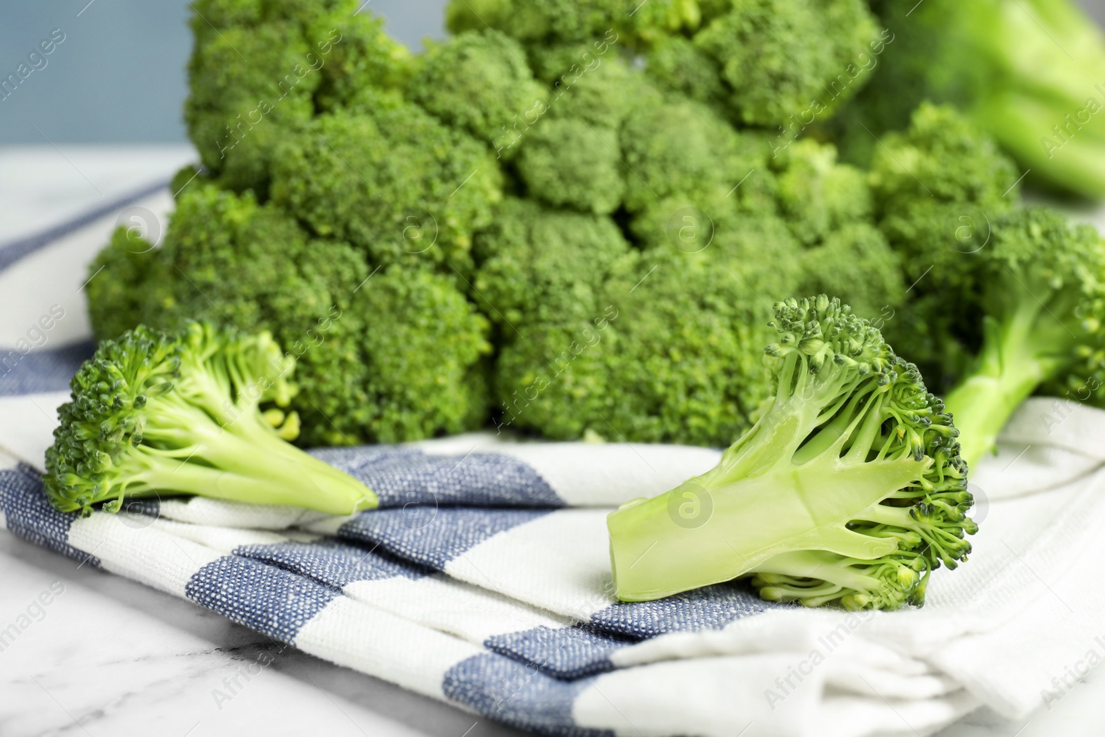 Photo of Fresh green broccoli on white marble table, closeup